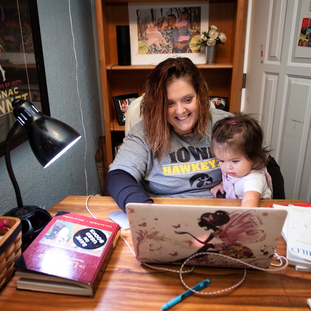 A parent and a child sitting at a desk looking at a laptop and smiling
