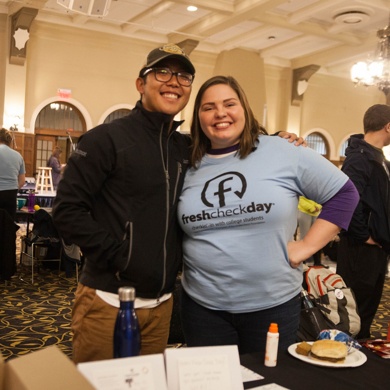 two students standing behind table wearing fresh check day t-shirts