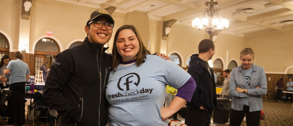two students standing behind table wearing fresh check day t-shirts