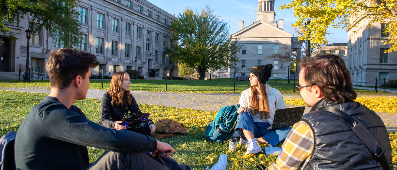 Four students having pleasant conversations in front of old capitol museum 