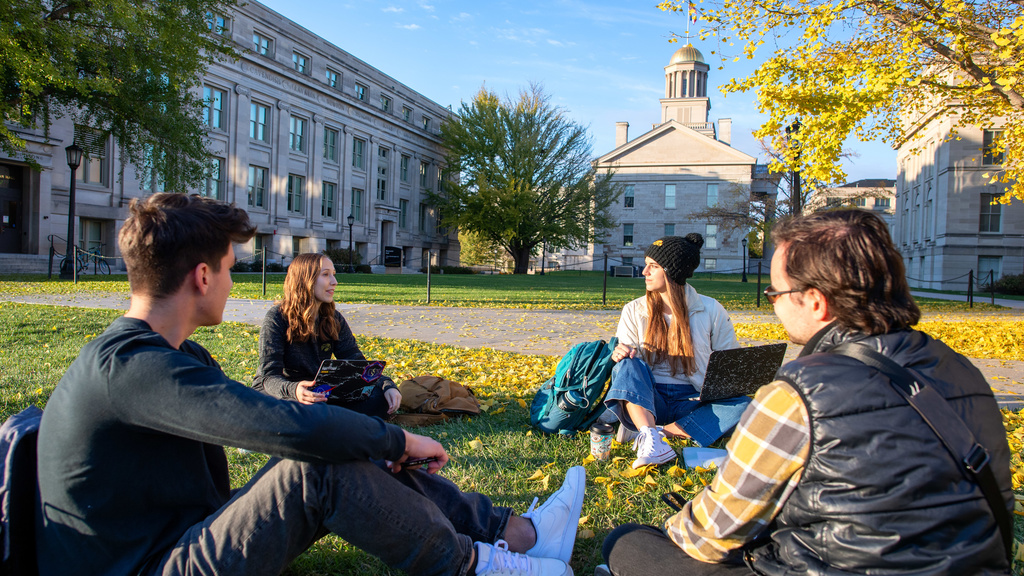 Four students having pleasant conversations in front of old capitol museum 